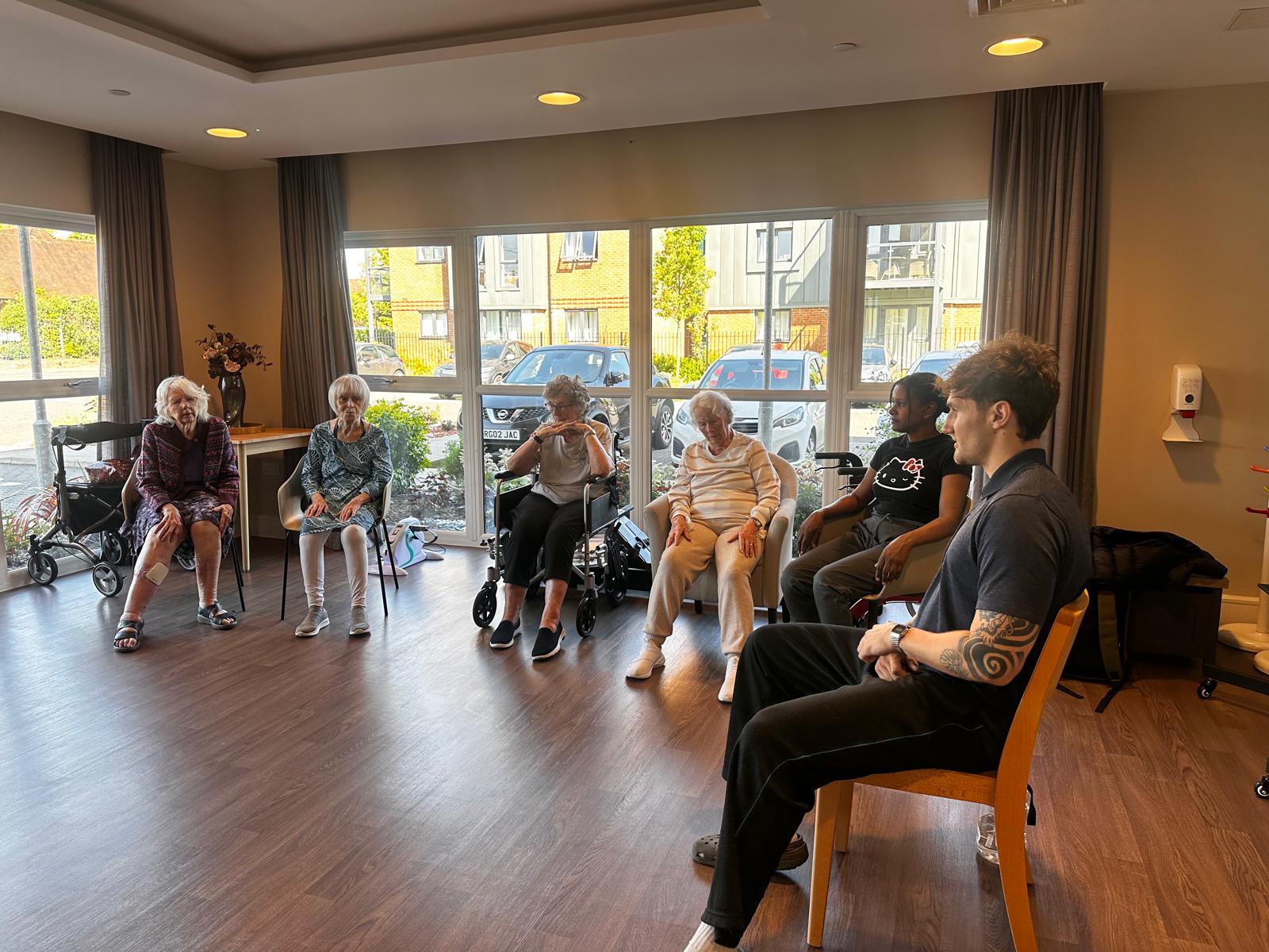 Alex leading an inclusive seated exercise session with care-home residents